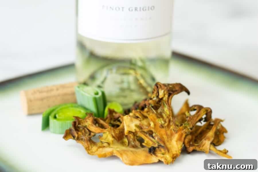 Umami Mushroom Jerky 2 Crispy Maitake mushroom jerky on a white plate, with a white wine bottle and cork in the background, suggesting a gourmet snack experience.