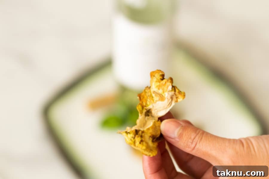 Umami Mushroom Jerky 11 Finished, crispy Maitake mushroom jerky artfully arranged on a plate, with a bottle of white wine in the soft-focused background, suggesting a perfect pairing.