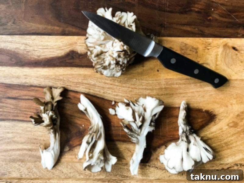 Umami Mushroom Jerky 4 Carefully sliced Maitake mushrooms arranged on a wooden cutting board next to a chef's knife, highlighting uniform pieces ready for marination.