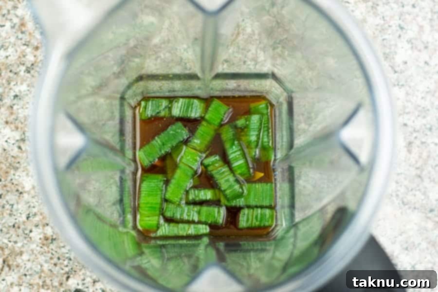 Umami Mushroom Jerky 6 The ingredients for the jerky marinade, including chopped leeks, being processed in a Vitamix blender, illustrating the blending step.