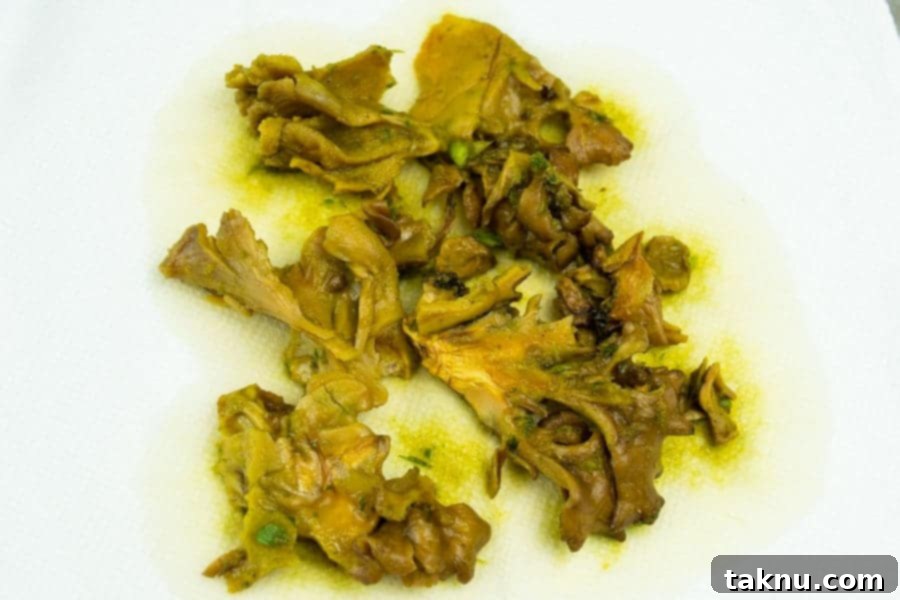 Umami Mushroom Jerky 9 Drained, marinated mushroom slices carefully laid out on paper towels to absorb excess liquid, revealing their vibrant, curry-infused color.