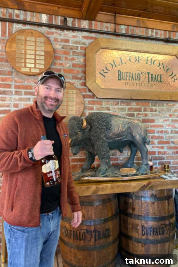 Blueberry Bourbon Marinated Venison Jerky 15 A person holds a bottle of Buffalo Trace bourbon, with the historic distillery buildings in the background.