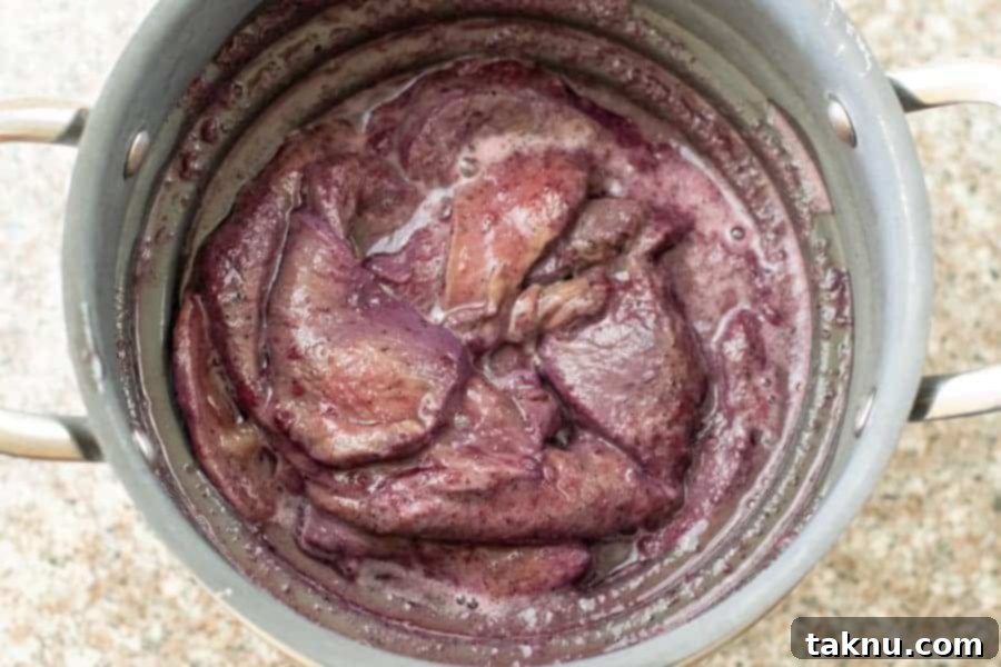 Blueberry Bourbon Marinated Venison Jerky 10 Marinated deer jerky strips expertly strained in a colander, removing excess liquid before drying.