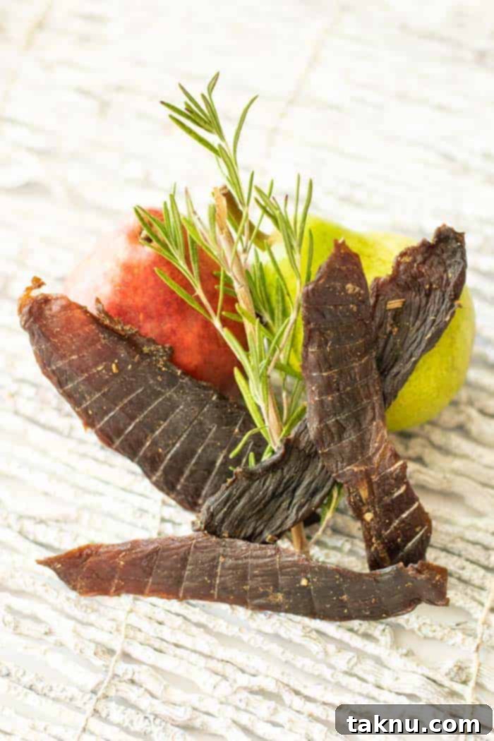 Rosemary and a pear with deer jerky on white background