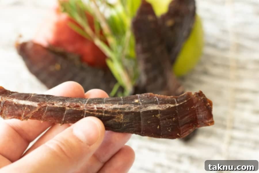 Deer jerky bending showing white fibers with pear in background