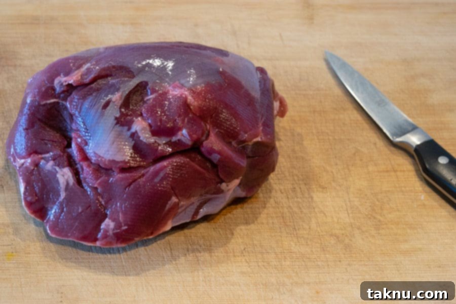 Venison roast on cutting board with a sharp knife, ready for trimming