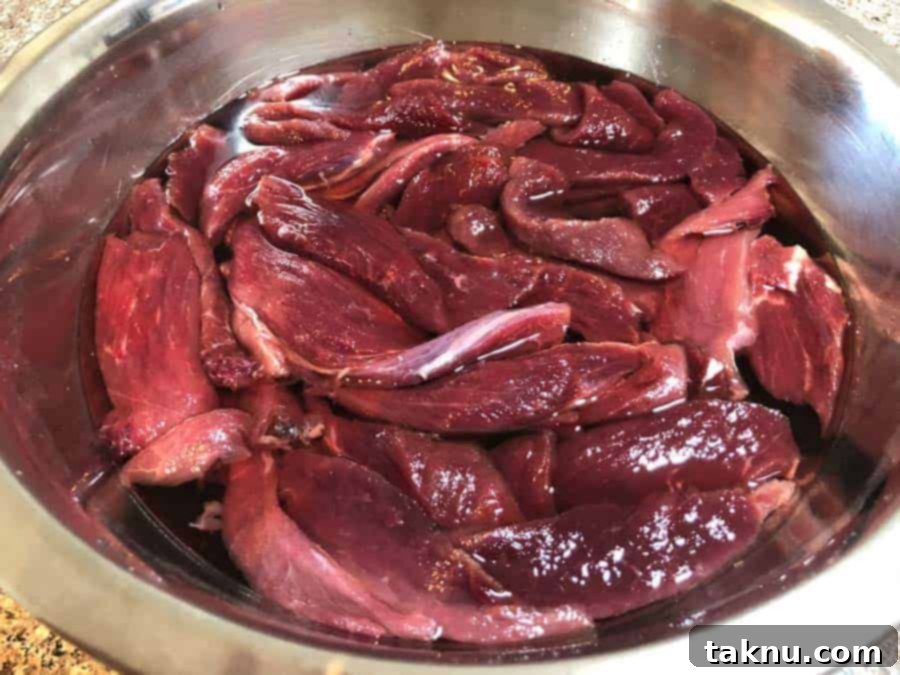 Venison strips soaking in a water and salt solution in a bowl to remove gamey flavor