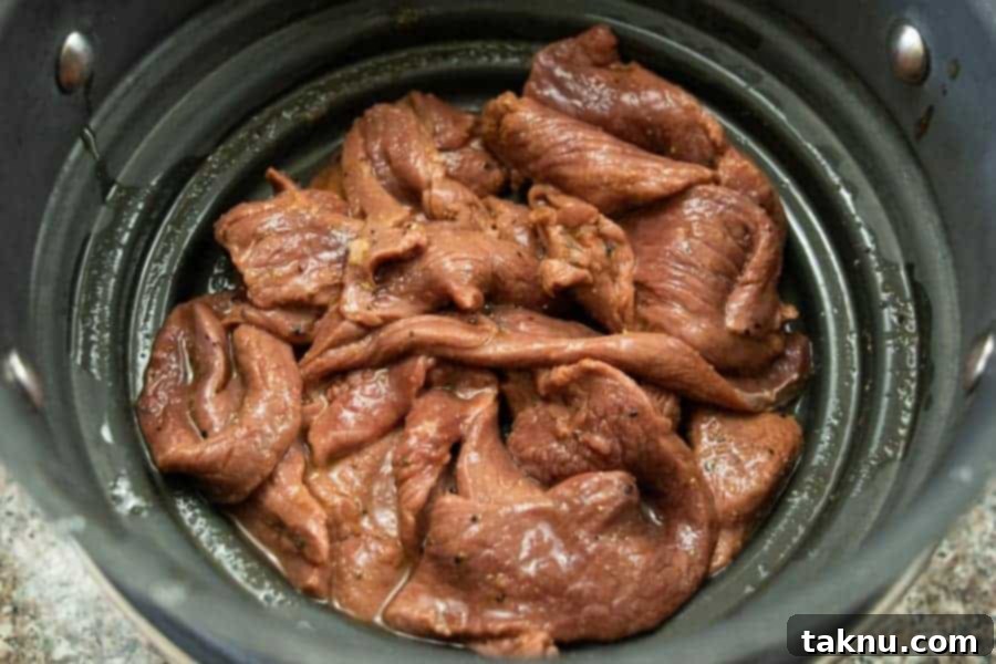 Sriracha jerky strips straining in a colander, removing excess liquid