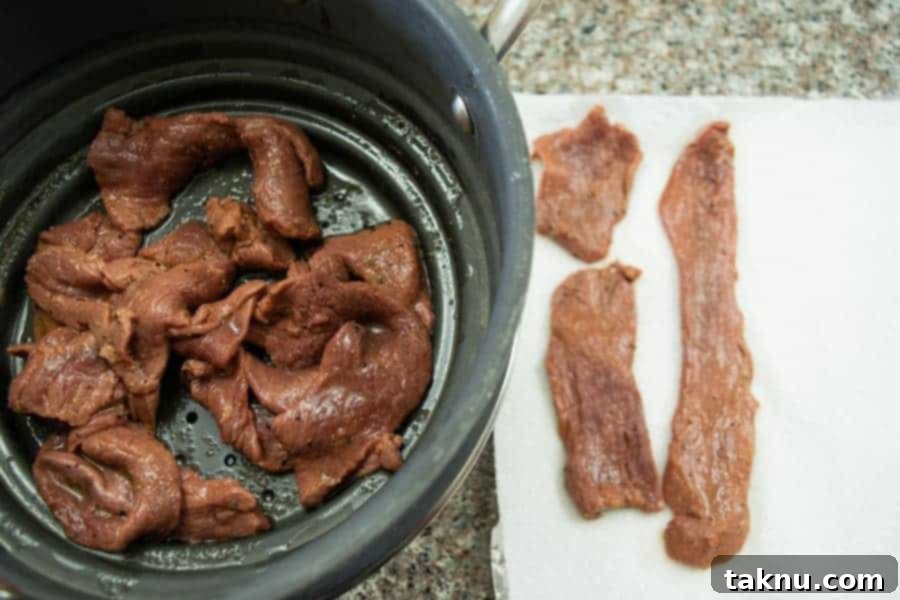 Sriracha jerky drying on paper towels before being placed in the dehydrator