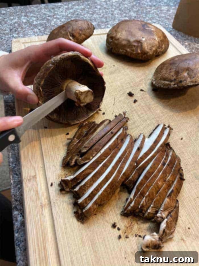 Hands slicing Portobello mushrooms in even strips on cutting board