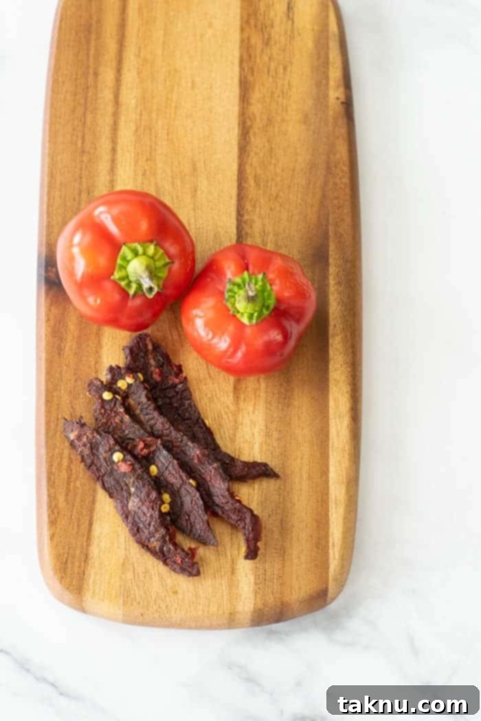 Blazing Cherry Beef Strips 16 Cherry bomb beef jerky on cutting board with peppers