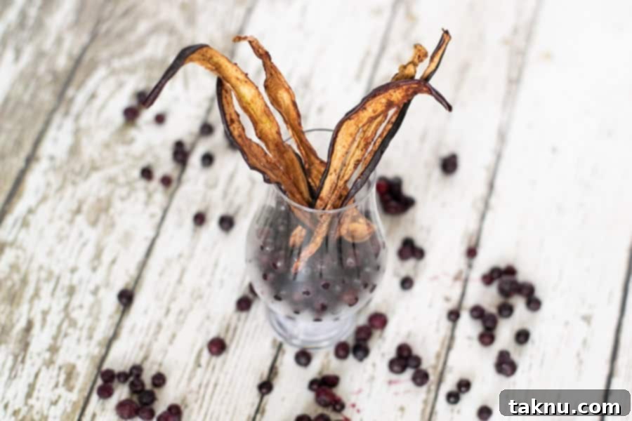 Fresh blueberries on a white wood table next to a glass jar filled with blueberry eggplant jerky slices