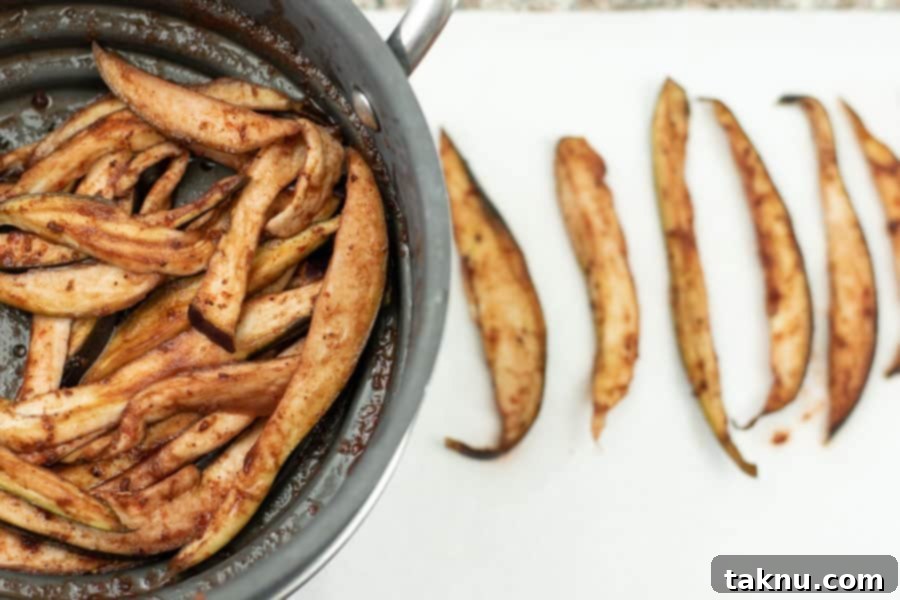 Blueberry eggplant jerky slices drying on paper towels after marinating, with blueberry bits visible