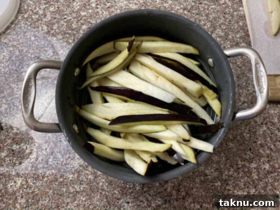 Eggplant slices thoroughly drained in a colander, showing the removal of excess saltwater