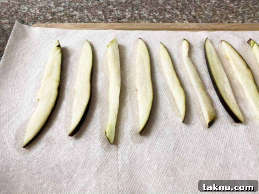 Wet eggplant slices laid out on paper towels, ready for air drying before marinating