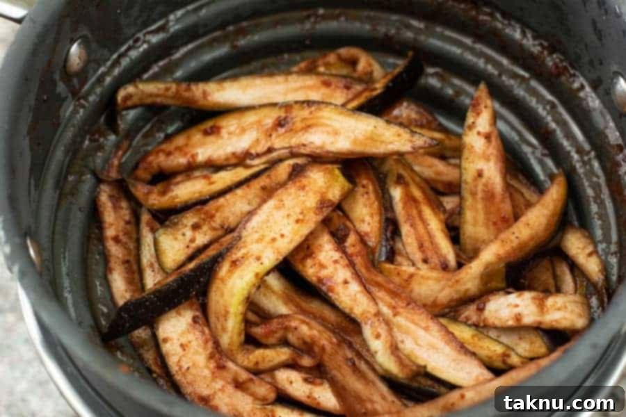 Marinated eggplant slices draining in a colander, showing the beautiful purple hue from the blueberry marinade
