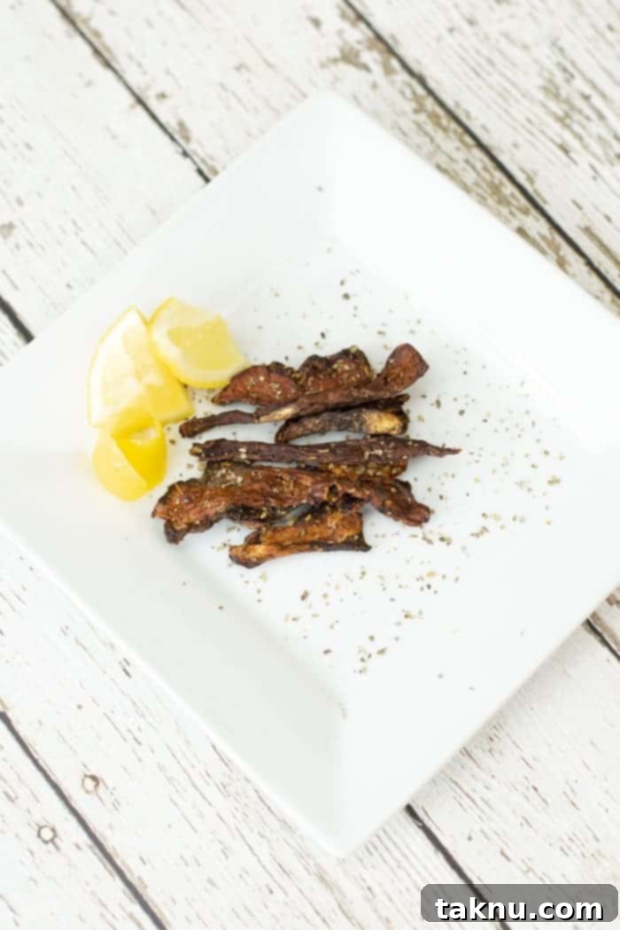 Brightly sliced lemons and savory porcini mushroom jerky neatly arranged on a white plate, highlighting a fresh, healthy snack