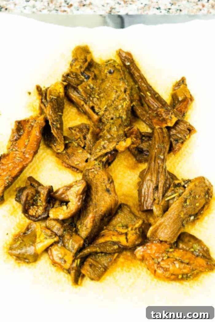 Marinated porcini mushroom slices spread on a paper towel, ready for drying