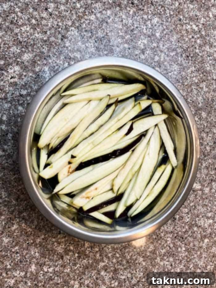 eggplant slices in bowl covered with water