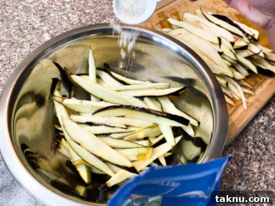 Sun-Kissed Eggplant Bites 4 Pouring salt into water bowl filled with eggplant slices