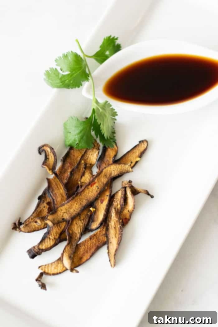 Tangy Umami Mushroom Bites 11 Mushroom jerky on white plate with green garnish and soy sauce in small dish