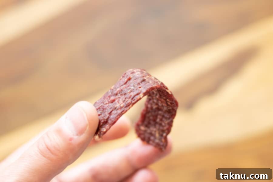 ground beef jerky strip being bent in half to test doneness