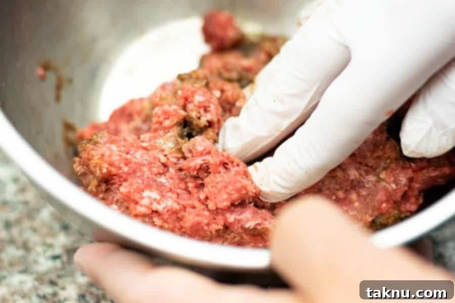 mixing marinade into ground beef by hand with gloves