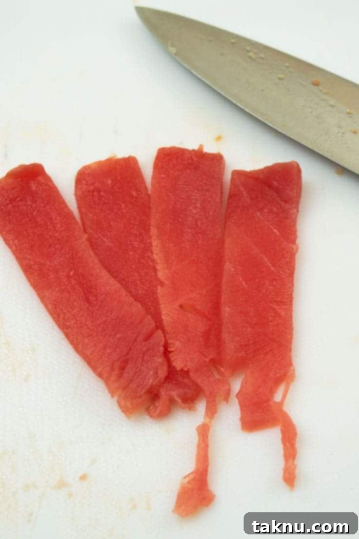 Zesty Inferno Tuna Strips 3 Tuna steak being sliced into thin strips for jerky preparation