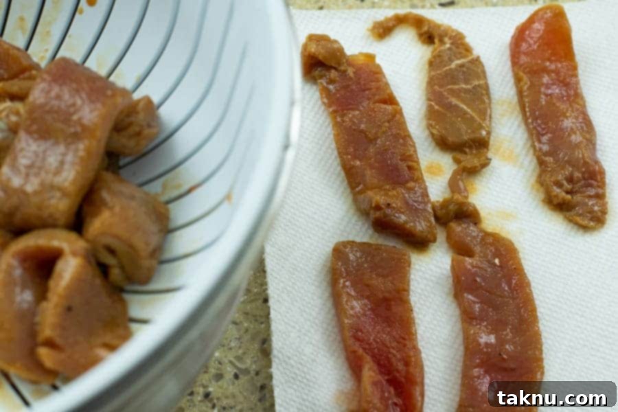 Zesty Inferno Tuna Strips 7 Strained tuna strips in a colander, with some laid out on paper towels for drying