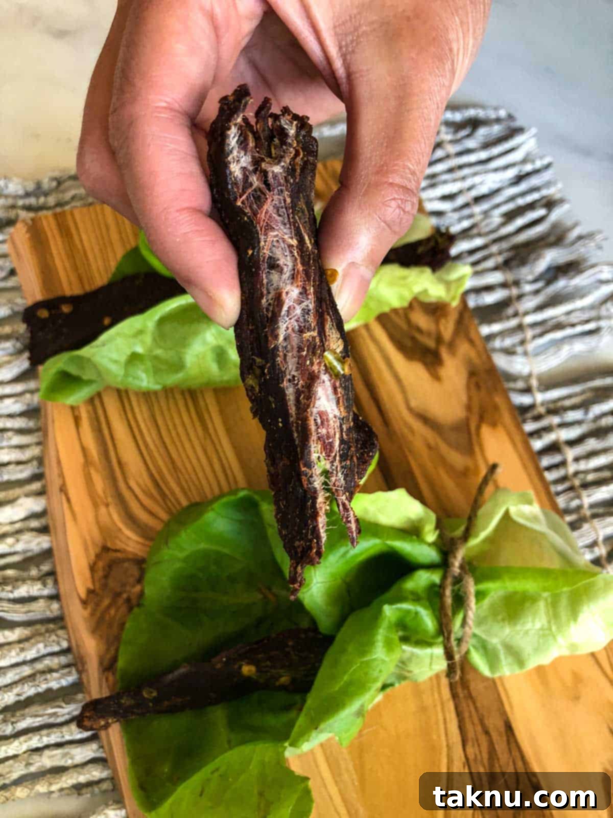 Bold Asian Venison Jerky 6 Deer jerky ripped in half showing it's finished with cutting board in background