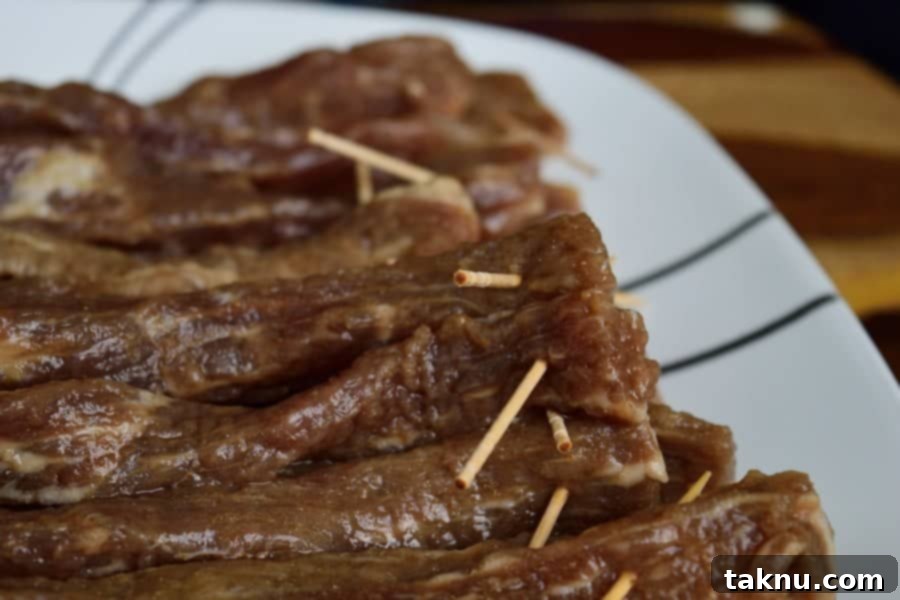 Beef strips marinating in brown sugar mixture in a large bowl.