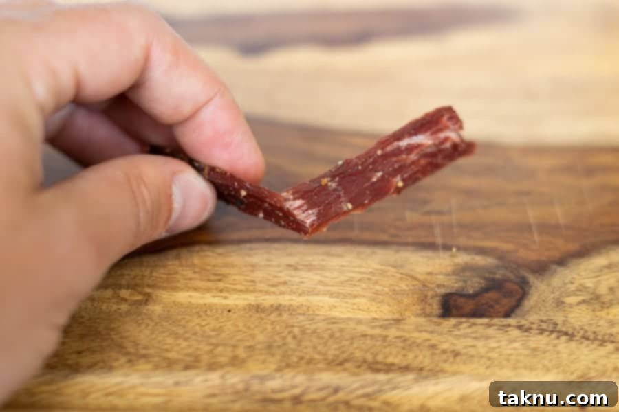 Demonstration of bending a piece of jerky to check for doneness.