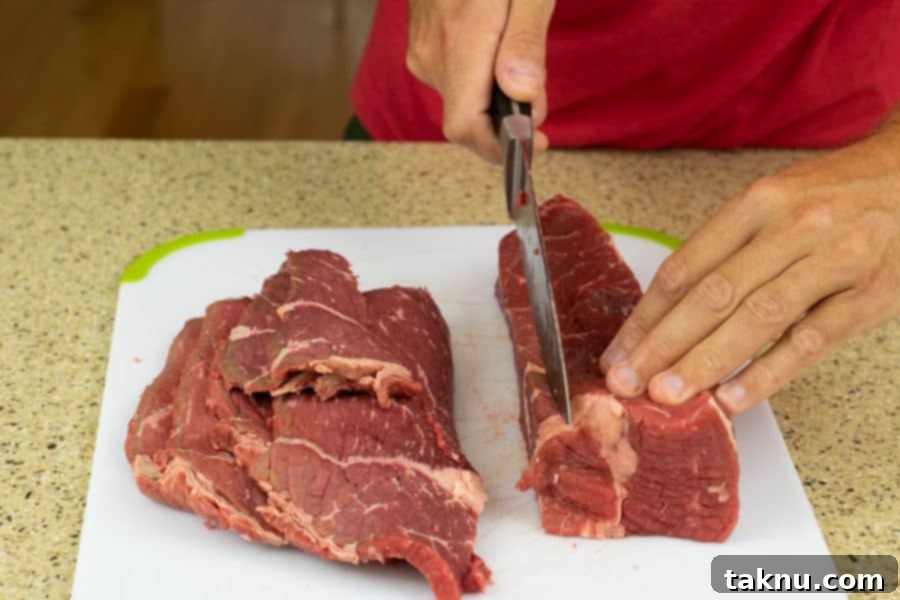 Zesty Beef Jerky 4 Slicing beef into strips for jerky on cutting board, demonstrating cutting technique