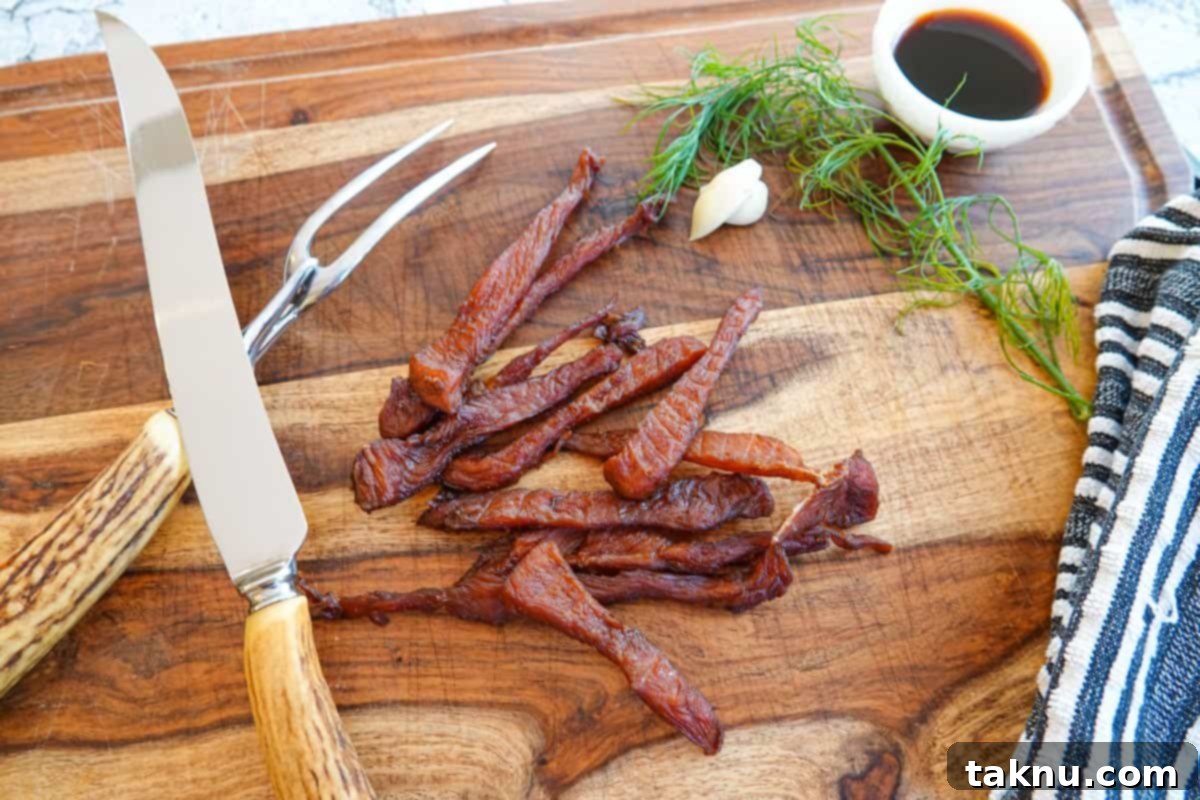Ultimate Turkey Jerky 9 Turkey jerky on cutting board with carving knife and dish of soy sauce