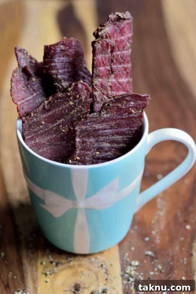 Bold Peppered Beef Jerky 8 beef jerky in blue mug on wood cutting board