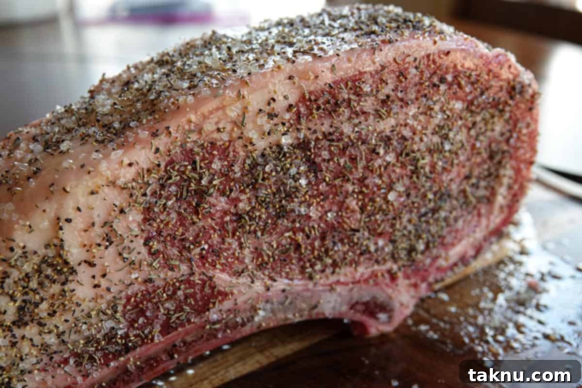 Prime rib roast generously seasoned with salt, pepper, and fresh thyme, ready for smoking.