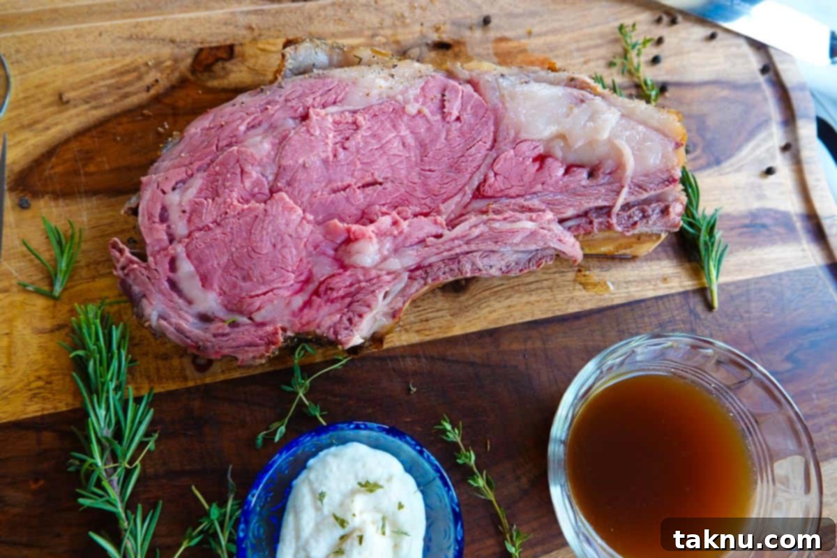 Perfectly sliced smoked prime rib roast on cutting board with creamy horseradish and au jus.