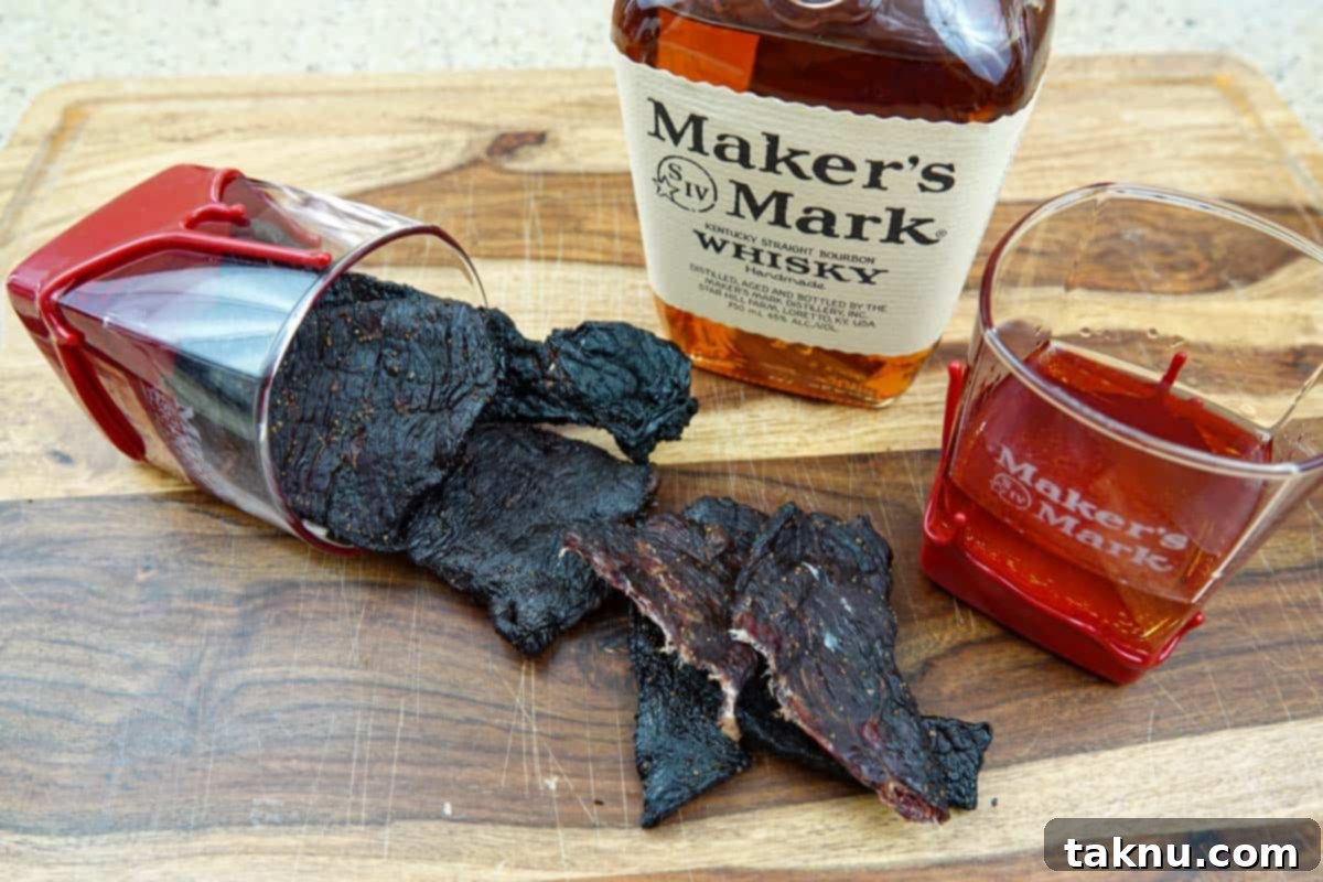 beef jerky on cutting board with bourbon bottle