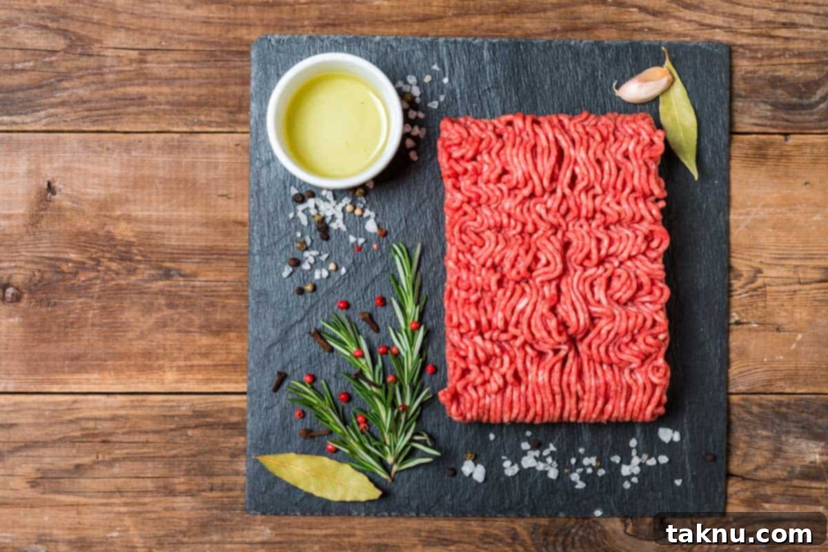 Fresh ground beef on a black slate with a sprinkle of spices.