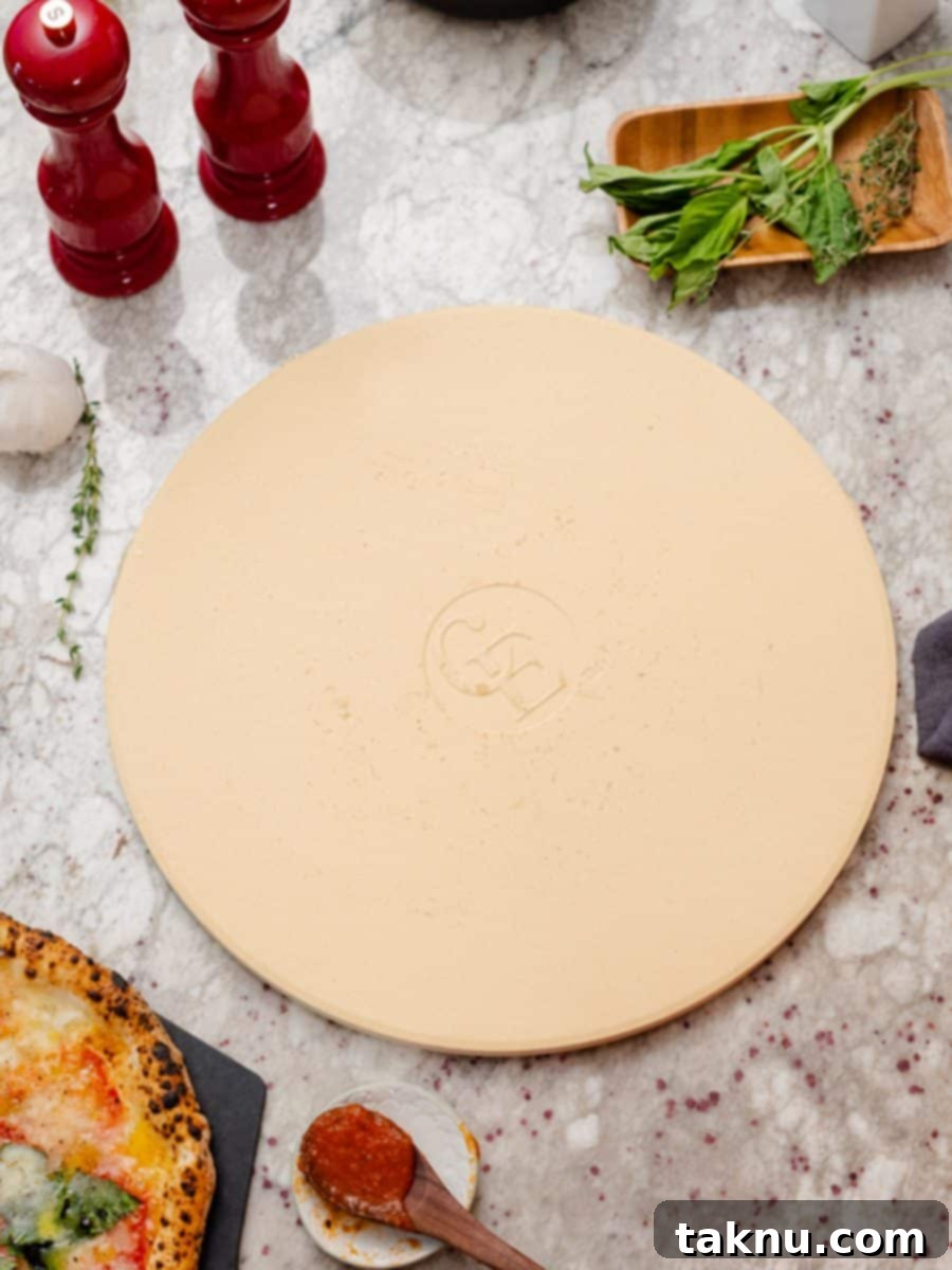 Smoky Cheesy Pizza Thirty Topping Inspirations 7 A pizza stone with a sprinkle of salt and pepper, accompanied by a spoon holding marinara sauce, depicting ingredients for a pizza.