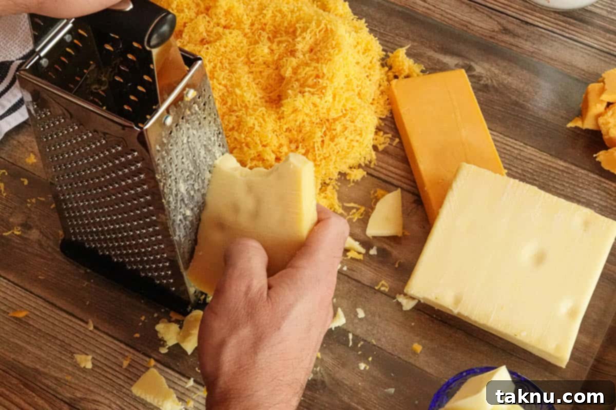Ultimate Smoked Mac and Cheese 4 Cheese being grated by hand on cutting board