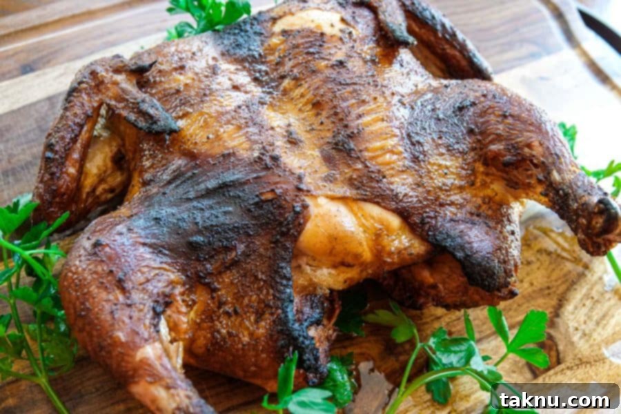 whole smoked chicken on cutting board with green garnish
