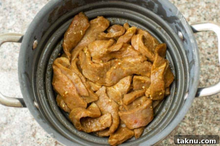 jerky strips stained of marinade in colander before drying