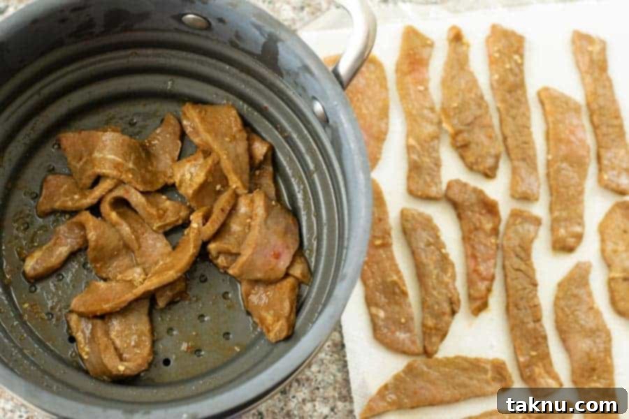 Patting dry jerky strips on paper towels after strained in colander