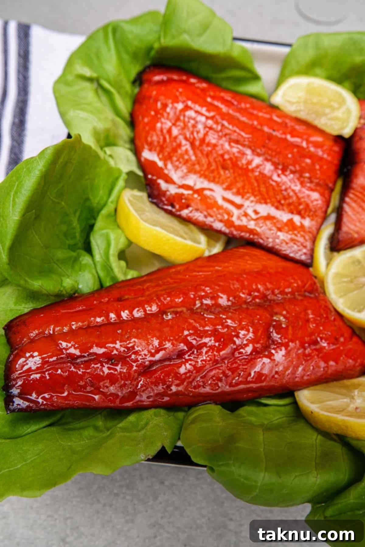 A stunning close-up of smoked salmon fillets presented on a bed of fresh lettuce, garnished with vibrant lemon slices, highlighting its perfect texture and color