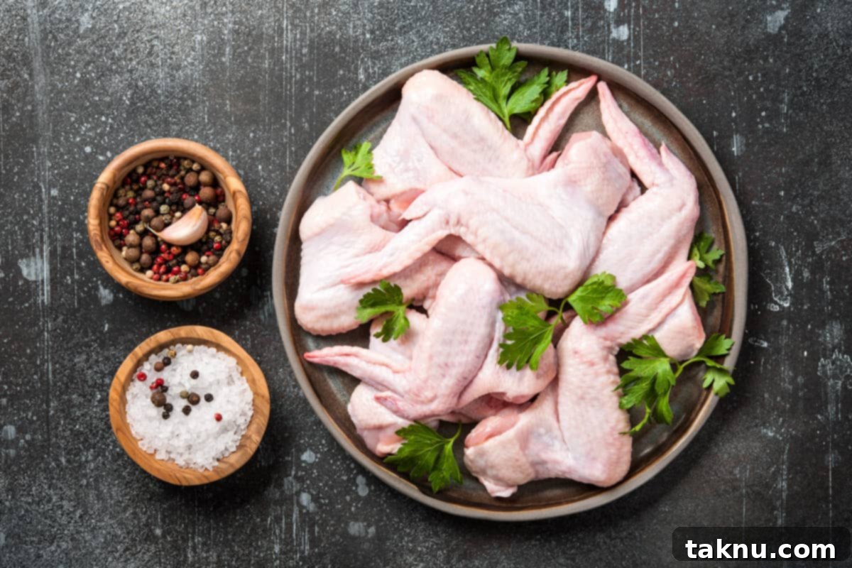 Irresistibly Crispy Smoked Chicken Wings 3 Raw chicken wings seasoned with spices on a white plate, ready for smoking.