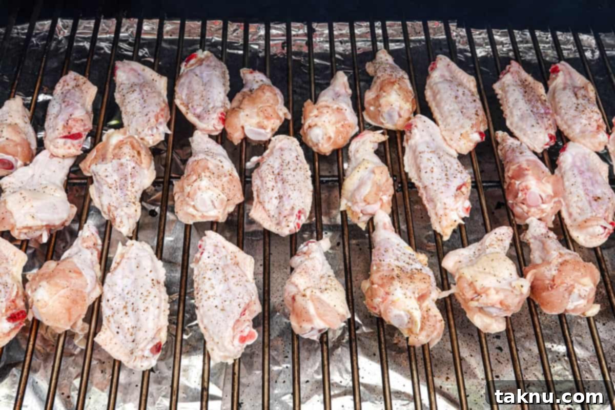 Irresistibly Crispy Smoked Chicken Wings 7 Crispy smoked chicken wings arranged neatly on a hot grill grate with visible smoke.