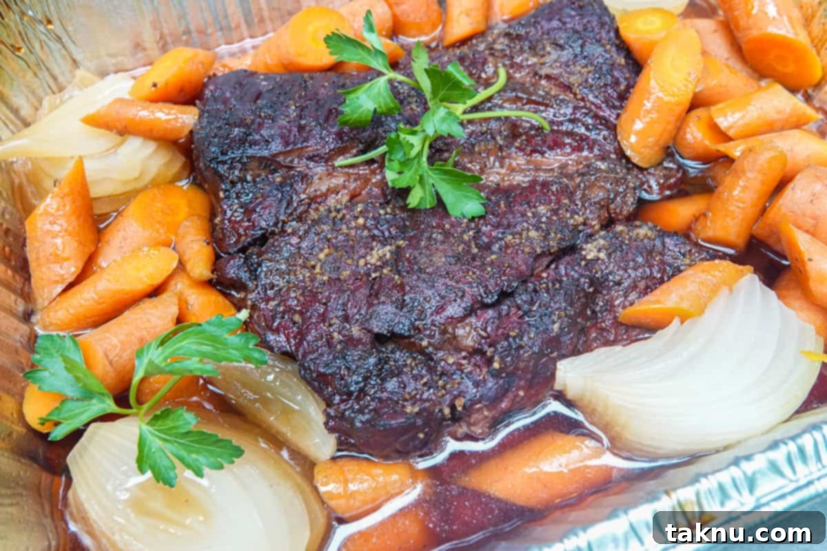 Tender smoked chuck pot roast with carrots and onions, ready to serve.
