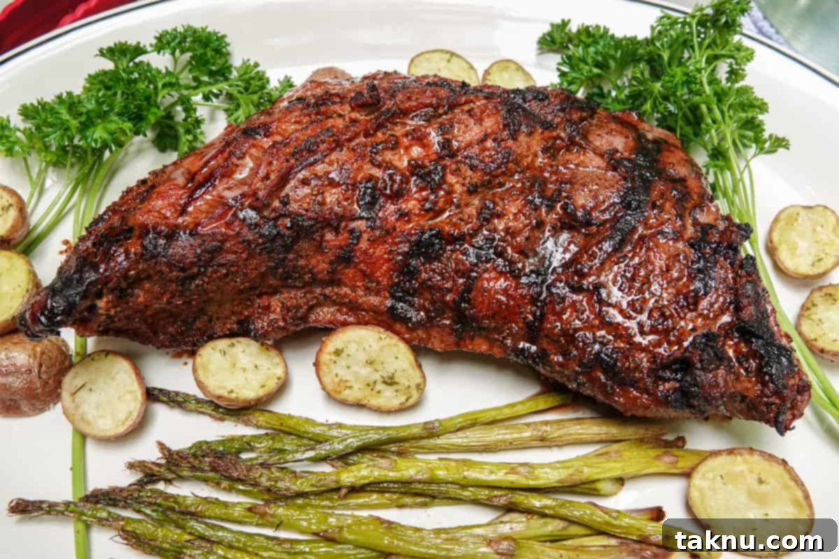 Smoked Tri-tip steak on a plate with roasted potatoes and green asparagus, ready to be served.