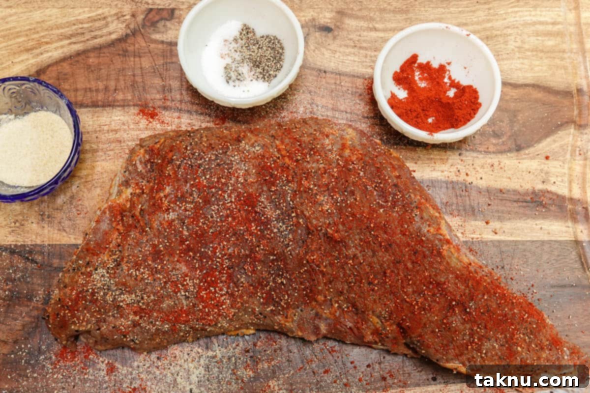Tri-tip steak generously seasoned with a dry rub, ready for smoking.